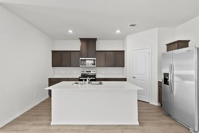 a white kitchen with a sink a refrigerator and cabinets