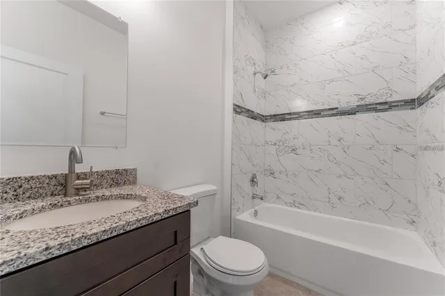 a bathroom with a granite countertop sink a toilet and bathtub