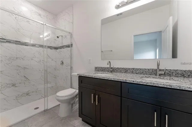 a bathroom with a granite countertop sink toilet a mirror and shower