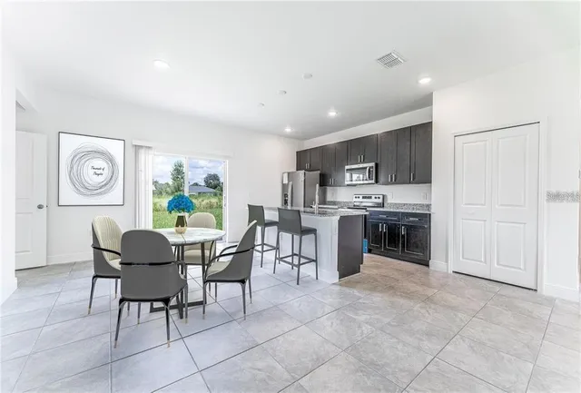 a dining room with furniture a chandelier and kitchen view