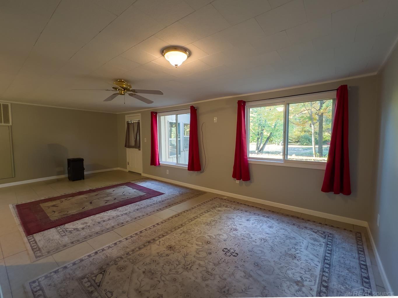 1123 Radov Road Gladwin, MI 48624 - Photo 8 of 29 The living room extends along the back of the house with unobstructed views of the water and greenery.