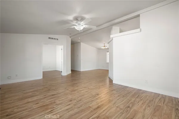 a view of an empty room with a window and wooden floor