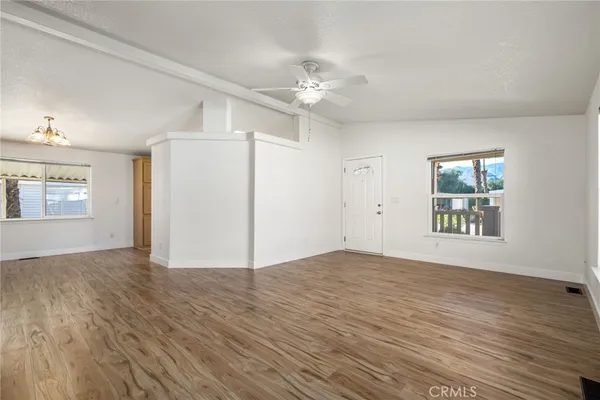 a view of an empty room with a window and wooden floor