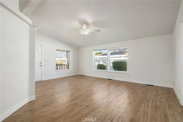 an empty room with wooden floor chandelier and windows