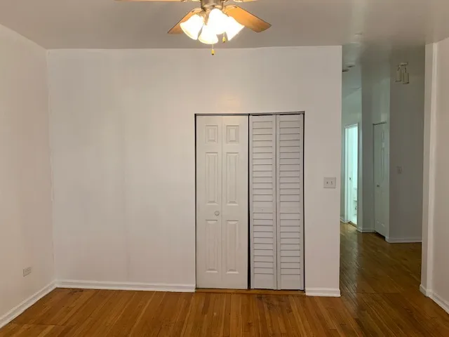 an empty room with wooden floor closet and windows
