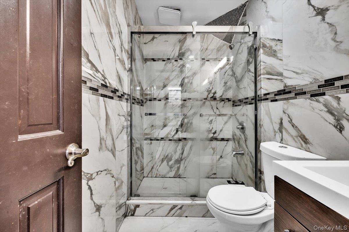 95-68 115th Street Queens, NY 11419 - Photo 10 of 28 Full bath with vanity, a marble finish shower, tile walls, and marble finish floors