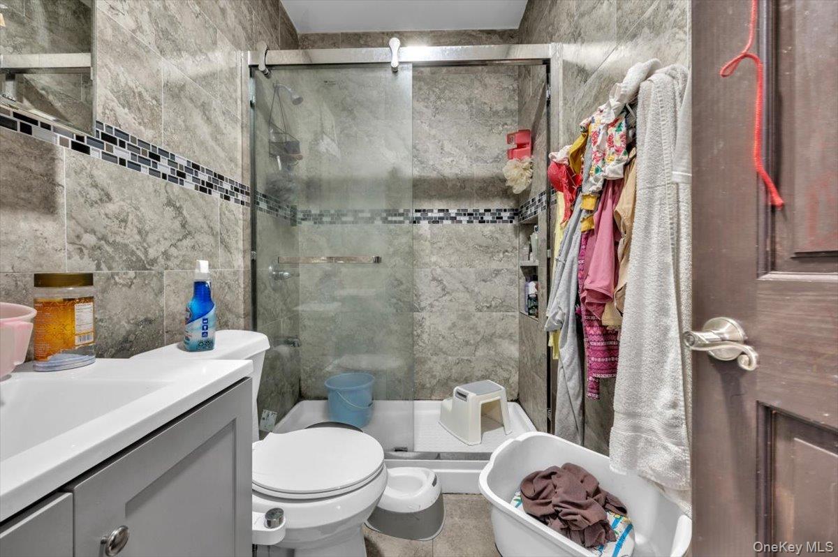 95-68 115th Street Queens, NY 11419 - Photo 18 of 28 Full bathroom featuring tile walls, vanity, and a shower stall