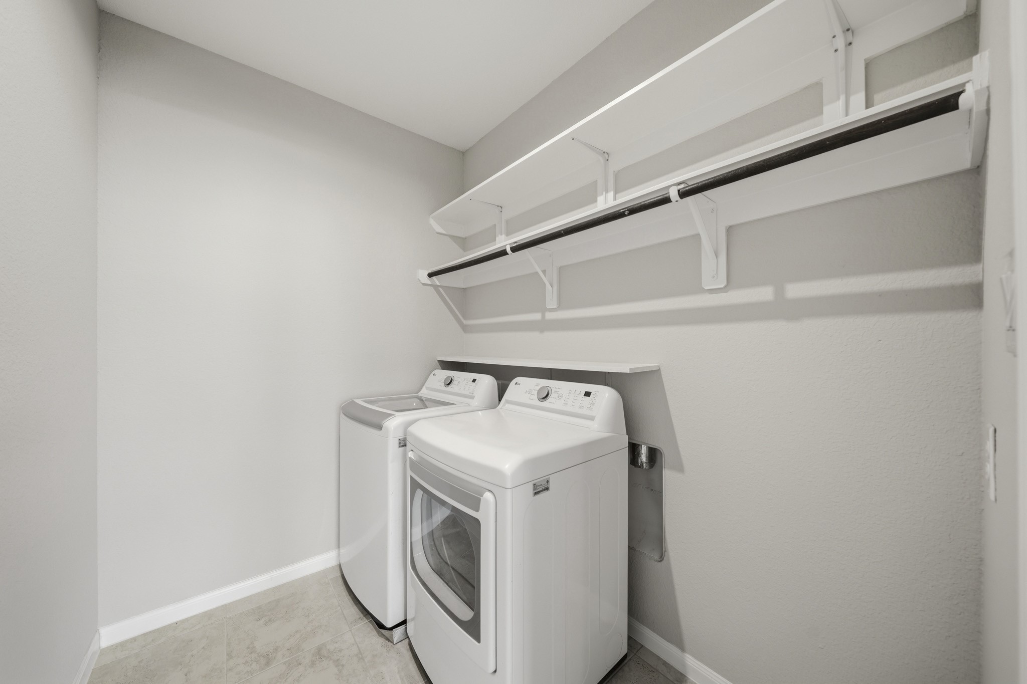 4103 Tranquil Square Road Houston, TX 77043 - Photo 33 of 39 A large and functional utility room features tile floors, a storage shelf, hanging rod, and an LG washer and dryer that convey with the home.