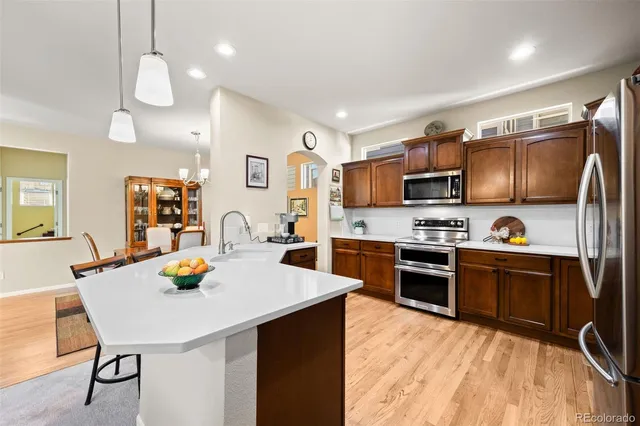 a kitchen with stainless steel appliances a stove a sink a refrigerator cabinets and dining table