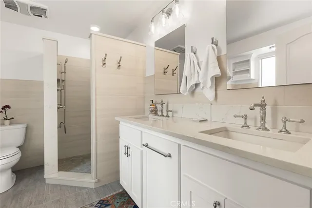 a bathroom with a granite countertop sink a toilet and a shower