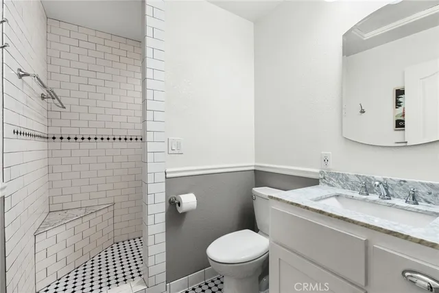 a bathroom with a granite countertop toilet a sink a shower and a mirror