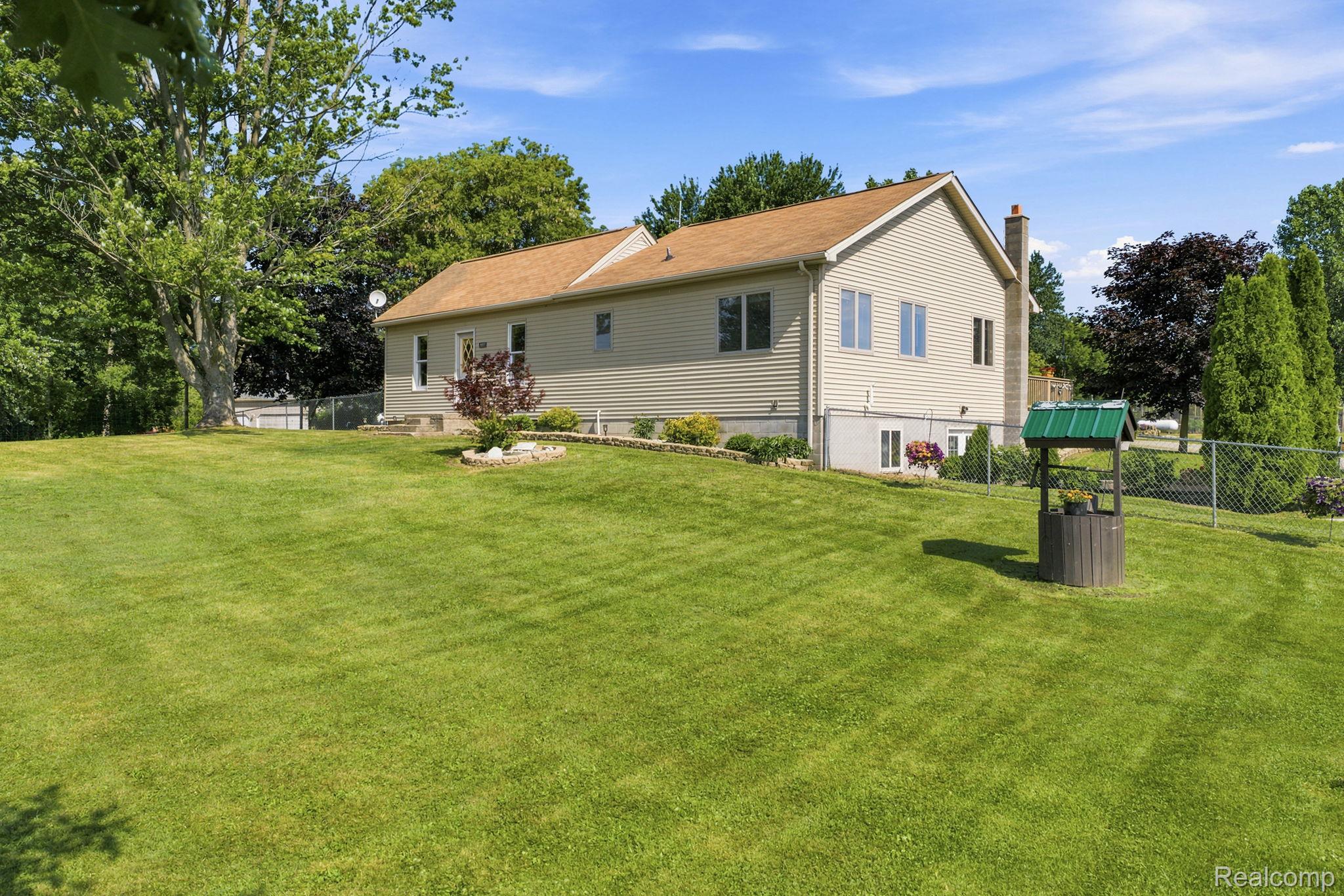 4201 Galbraith Line Road Croswell, MI 48422 - Photo 1 of 39 Spacious lawn area with mature trees and a decorative wishing well
