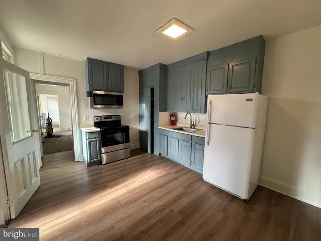 a kitchen with a refrigerator a stove top oven and wooden floor