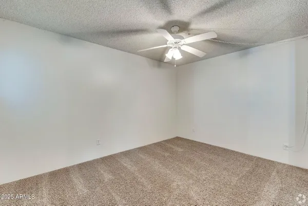 an empty room with a window and ceiling fan