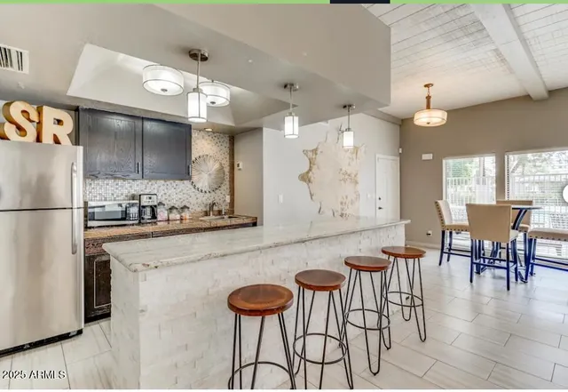 a kitchen with stainless steel appliances kitchen island granite countertop a table chairs and a refrigerator