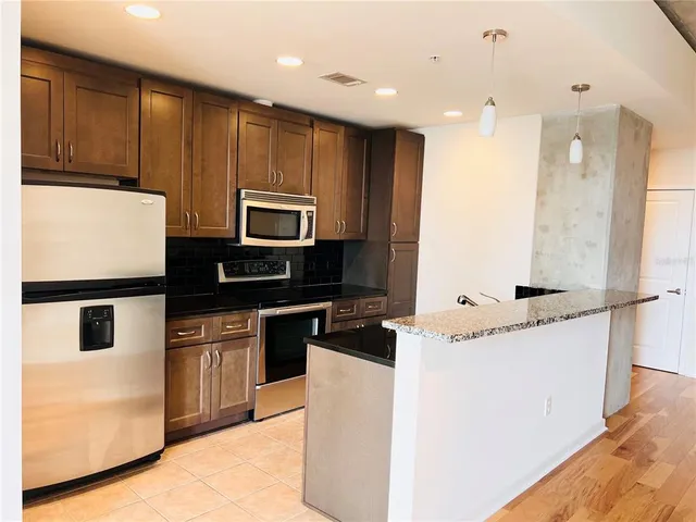 a kitchen with stainless steel appliances granite countertop a stove top oven a sink and a refrigerator