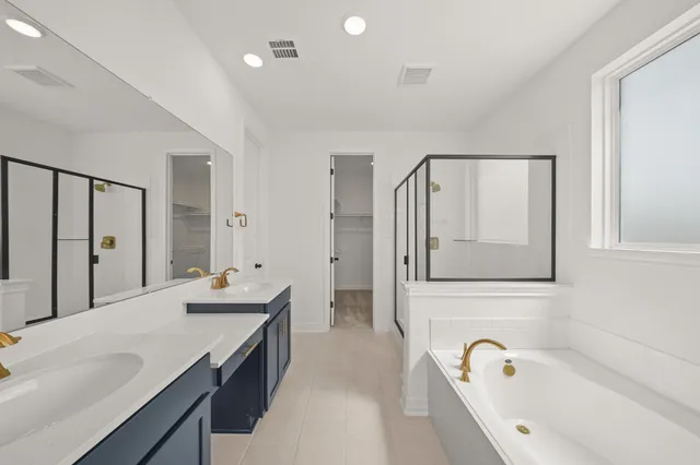 a spacious bathroom with a double vanity sink a mirror and a bathtub