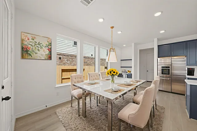 a kitchen with a dining table chairs and refrigerator