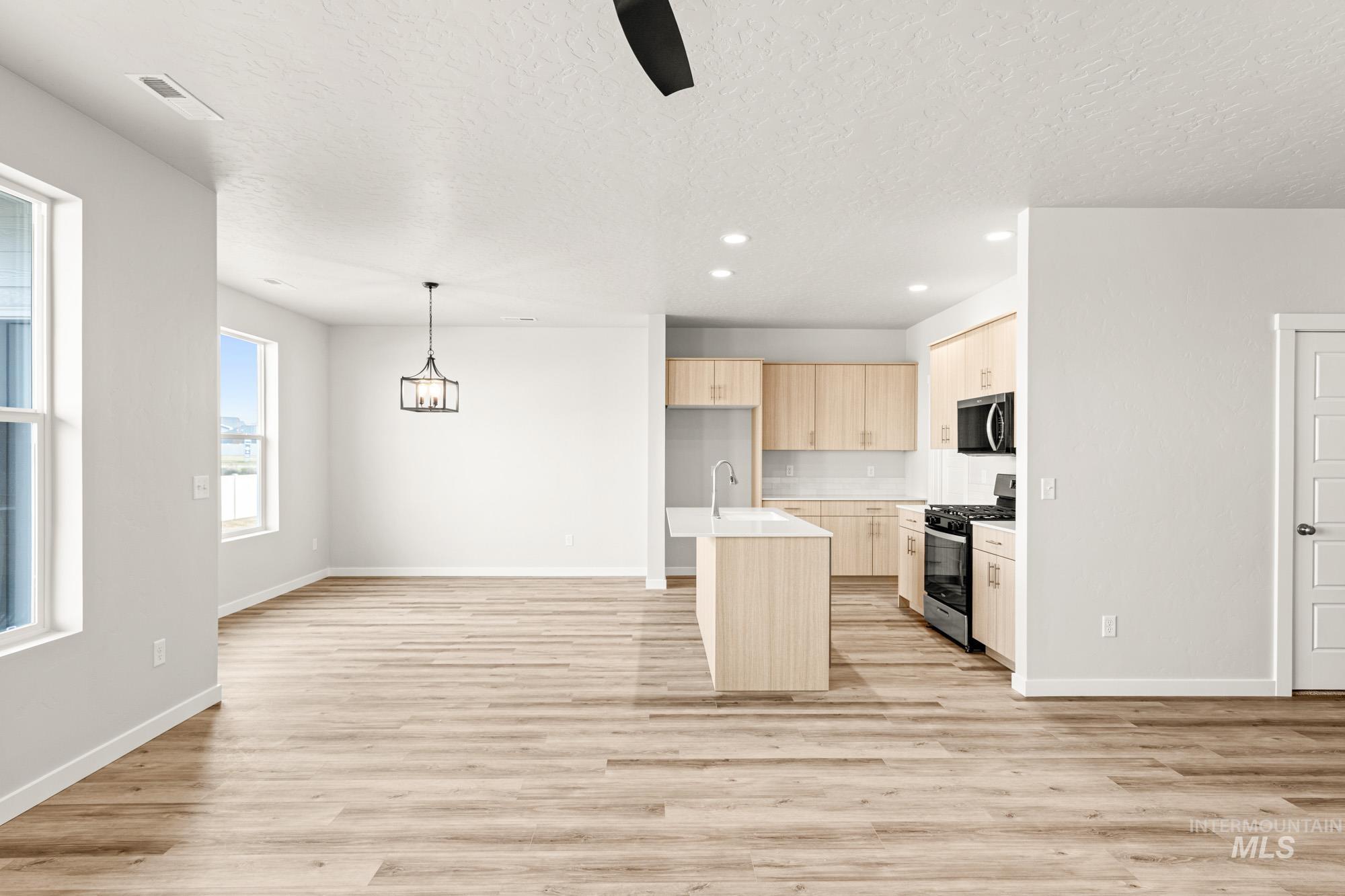12865 Decatur Street Nampa, ID 83651 - Photo 10 of 20 Open-concept living area with wood-finish flooring, a kitchen island, recessed lighting, light-toned cabinetry, and black appliances