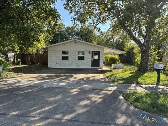 a front view of a house with a yard and trees
