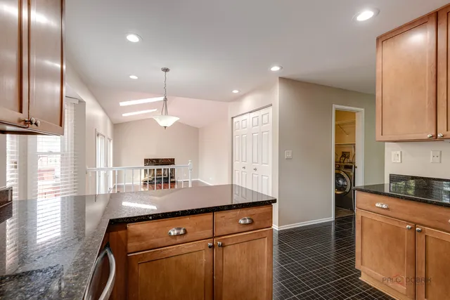 a kitchen with kitchen island granite countertop a sink cabinets and stainless steel appliances