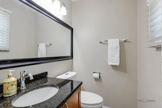 a bathroom with a granite countertop toilet sink and mirror