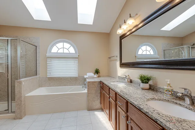 a bathroom with a granite countertop bathtub a sink and a window