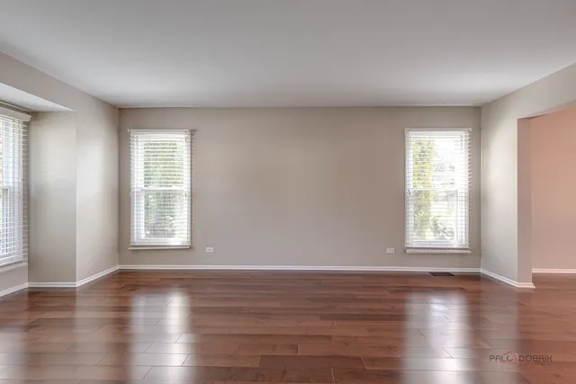 an empty room with wooden floor and windows with curtains view