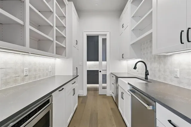 a view of a kitchen with kitchen island a sink wooden floor and stainless steel appliances
