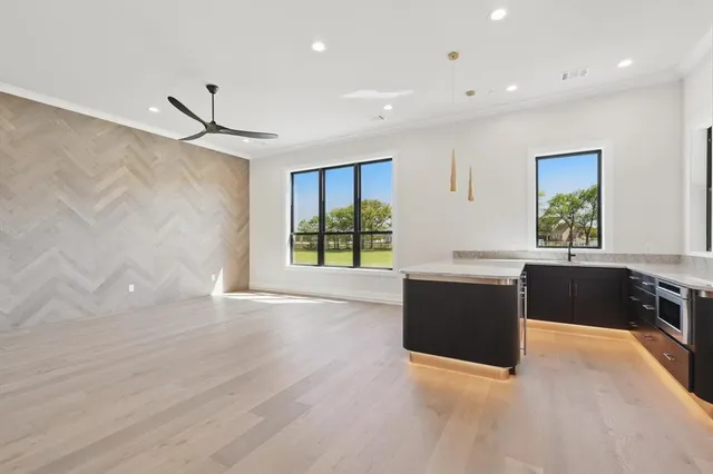 a large white kitchen with wooden floors and a large window