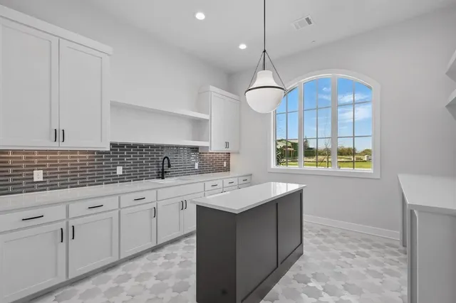 a kitchen with kitchen island granite countertop a sink a counter space appliances and cabinets