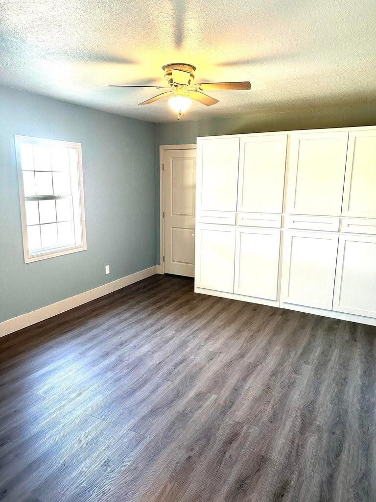 1704 West 6th Plainview, TX 79072 - Photo 6 of 13 an empty room with wooden floor and windows