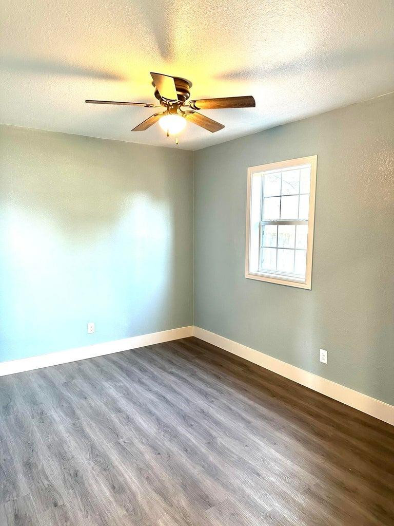 1704 West 6th Plainview, TX 79072 - Photo 8 of 13 an empty room with wooden floor fan and windows