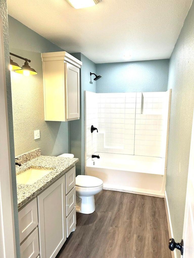 1704 West 6th Plainview, TX 79072 - Photo 9 of 13 a bathroom with a granite countertop sink toilet a large mirror a vanity and shower