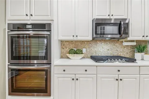 a kitchen with granite countertop white cabinets and stainless steel appliances