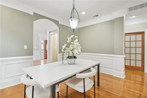 a dining room with wooden floor a chandelier a wooden table and chairs