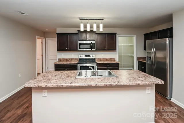 a large kitchen with kitchen island a sink counter top space cabinets and stainless steel appliances