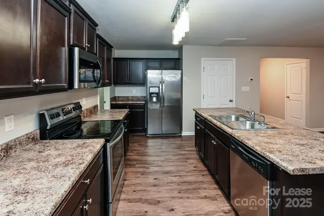 a large kitchen with stainless steel appliances granite countertop plenty wooden cabinets counter space and a sink