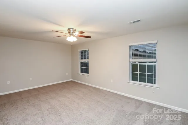 an empty room with window and ceiling fan