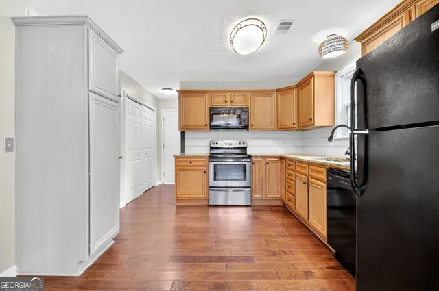 a kitchen with stainless steel appliances granite countertop a refrigerator a stove a sink and a microwave