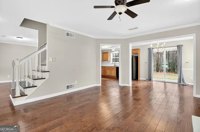 a view of an empty room with wooden floor fireplace and a window