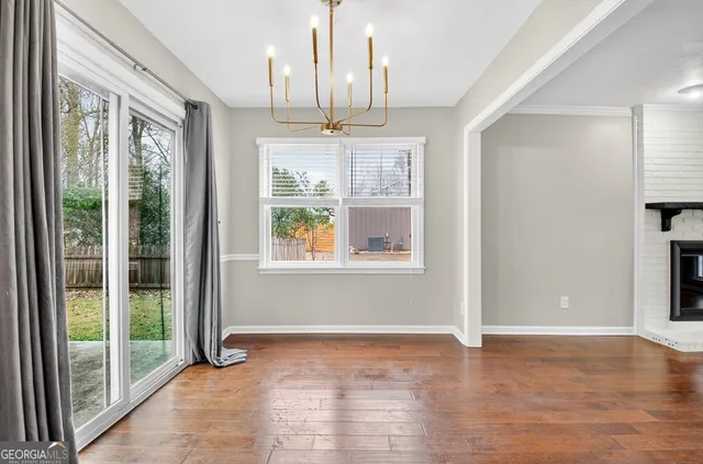a view of an empty room with window and wooden floor