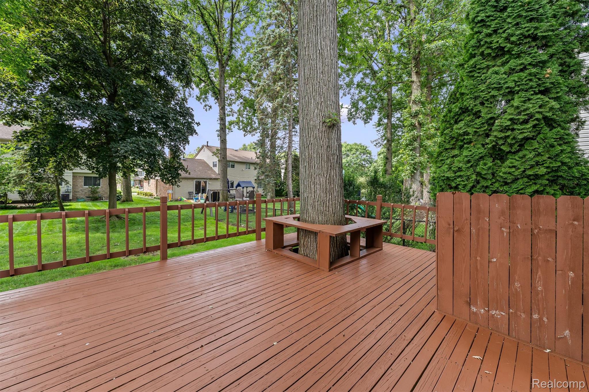 2118 Rutgers Drive Troy, MI 48085 - Photo 35 of 39 Expansive wooden deck featuring a built-in tree surround bench and a wooden privacy fence