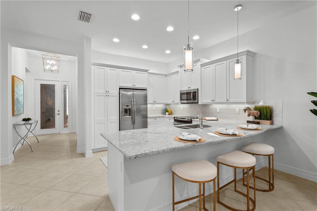 13459 Sumter Lane Naples, FL 34109 - Photo 6 of 40 a kitchen with stainless steel appliances granite countertop a stove a sink island and chairs