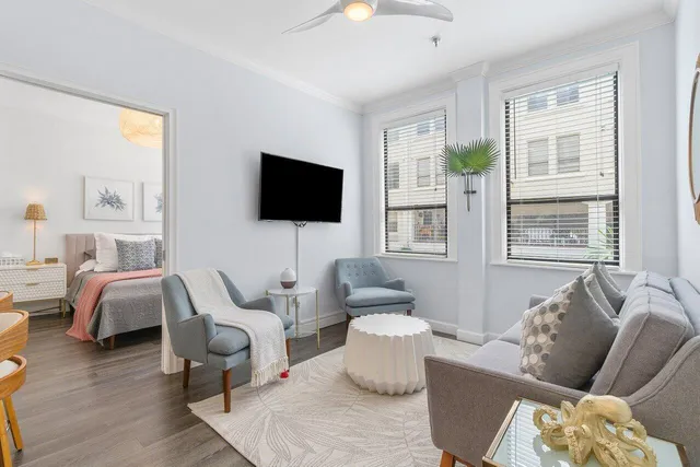 a living room with furniture a flat screen tv and windows