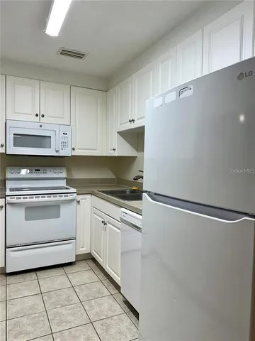 a kitchen with granite countertop white cabinets and white appliances