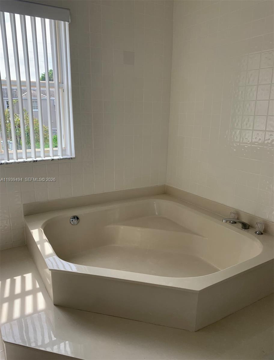 6950 Southwest 55th Terrace East Miami, FL 33155 - Photo 12 of 16 a white bath tub sitting in a bathroom next to a window