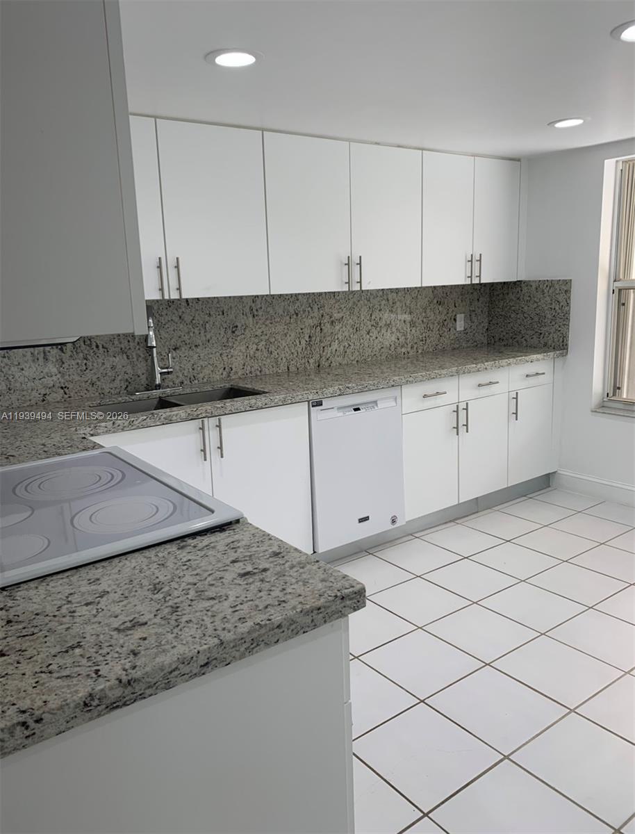 6950 Southwest 55th Terrace East Miami, FL 33155 - Photo 7 of 16 a kitchen with granite countertop white cabinets and a sink