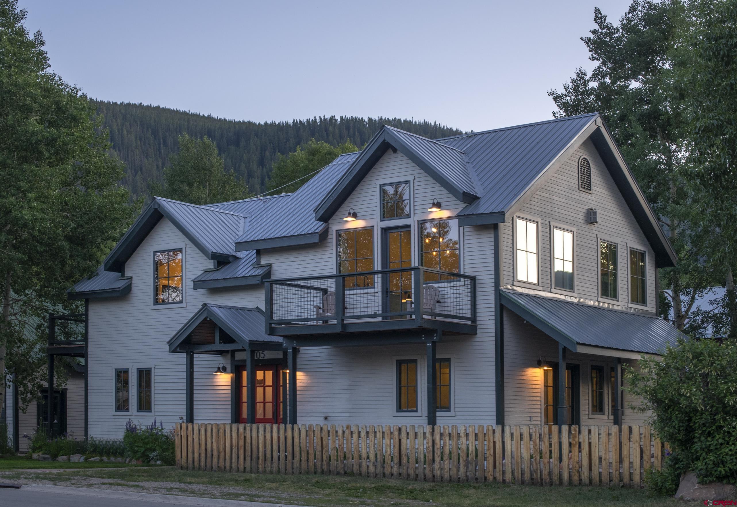 705 9th Street Crested Butte, CO 81224 - Photo 11 of 44 a view of a white house with large windows and a small yard