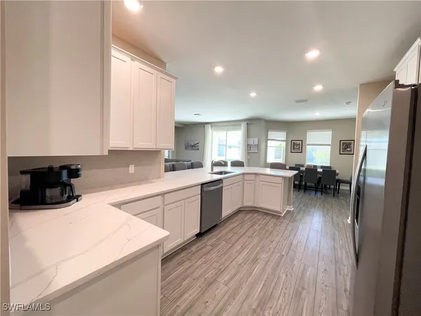 a kitchen with a refrigerator a sink dishwasher stove and white cabinets with wooden floor